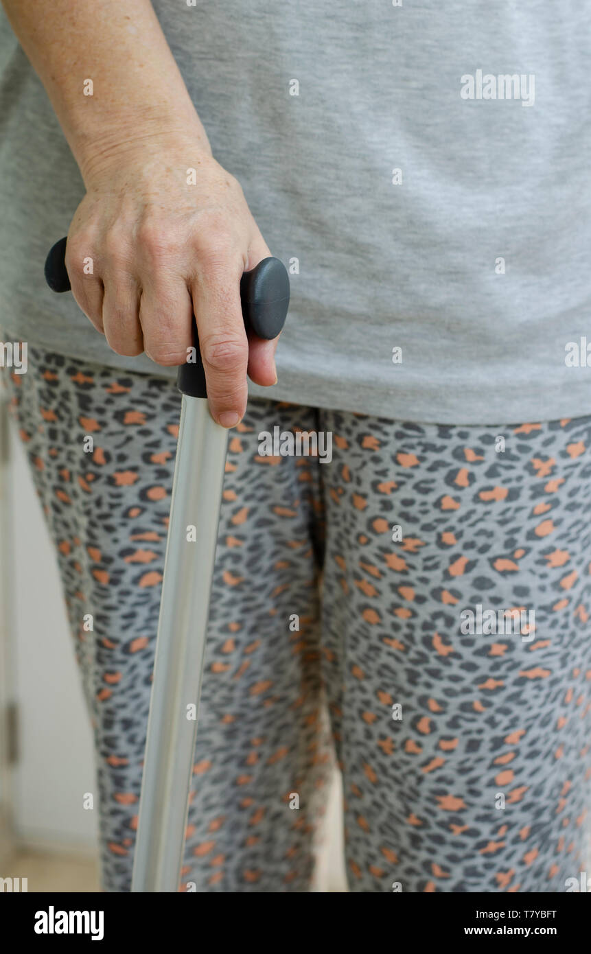 Senior woman standing with her hands on the handles of a walking cane. Rehabilitation and