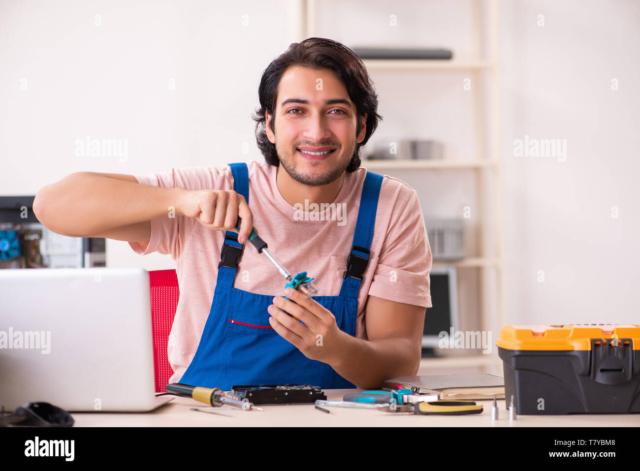 Young male contractor repairing computer Stock Photo