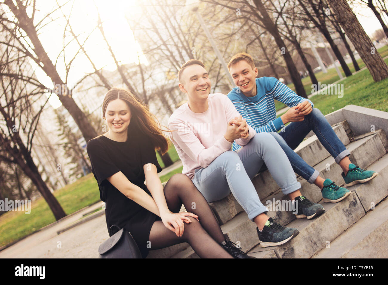 Group of friends Millennials students teenagers sitting at city street, friendship  Stock Photo