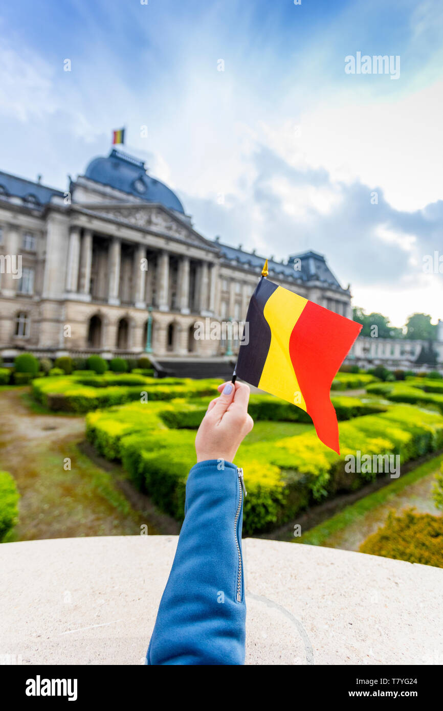 Royal Palace of Brussels and flag of Belgium in female hand, Belgium Stock Photo