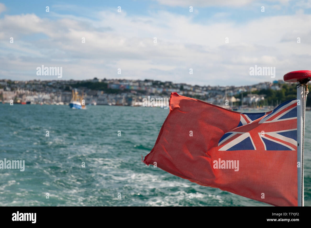 British maritime flag 'Red Ensign' or 'Red Duster' waving in the wind on the back of a motored boat. Stock Photo