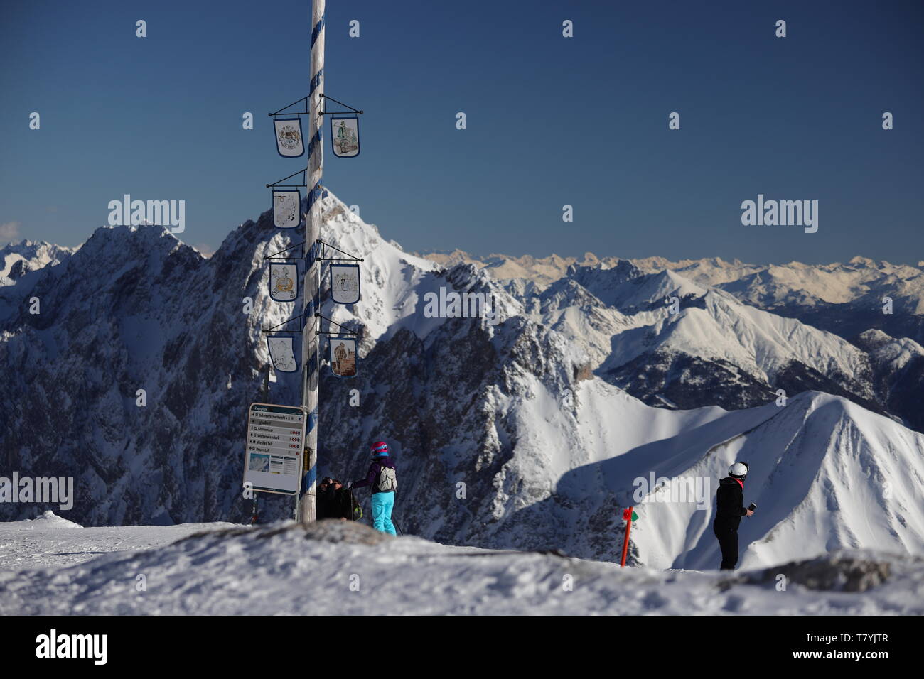 Ein Wegweiser zeigt den Besuchern der Zugspitze den Weg zu wichtigen Zielen. Im Hintergrund ein grandioses Alpenpanorama Stock Photo