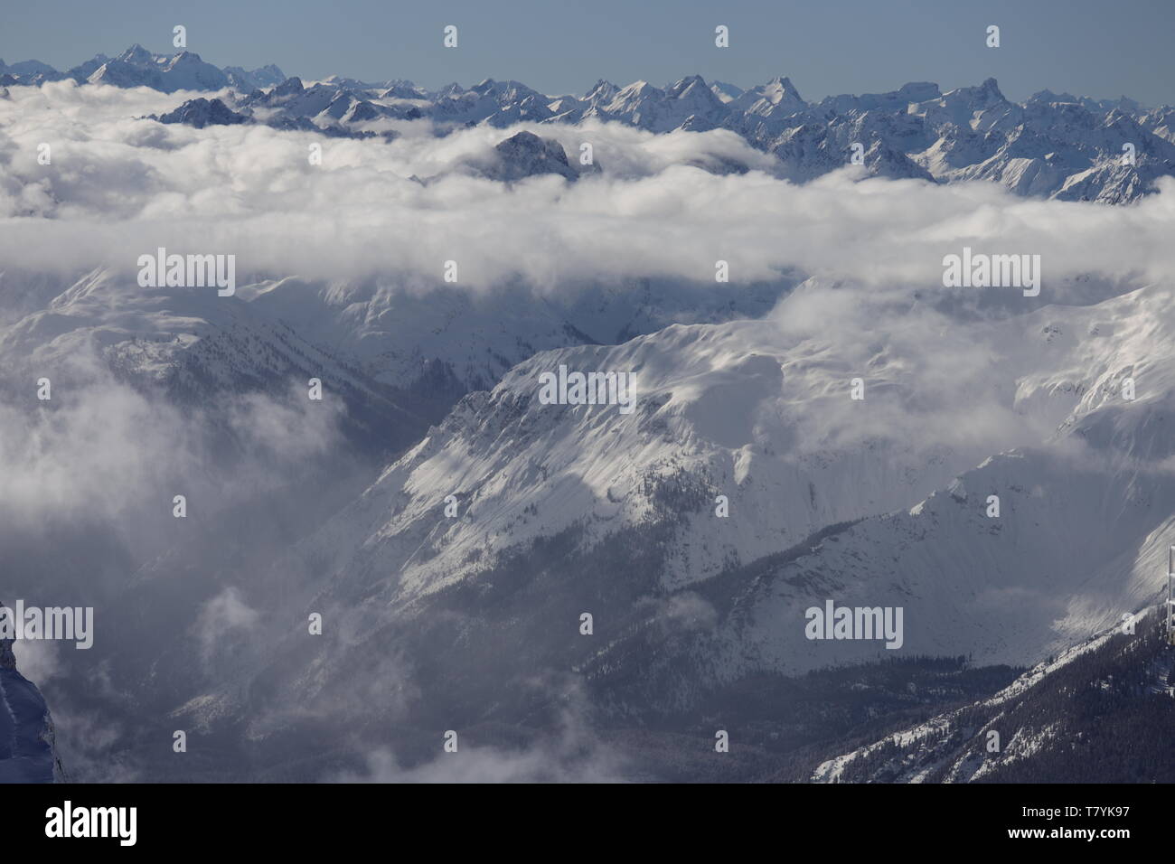 Blick über die verschneiten Gipfel der Alpen. Einige Täler liegen unter Wolken. Stock Photo