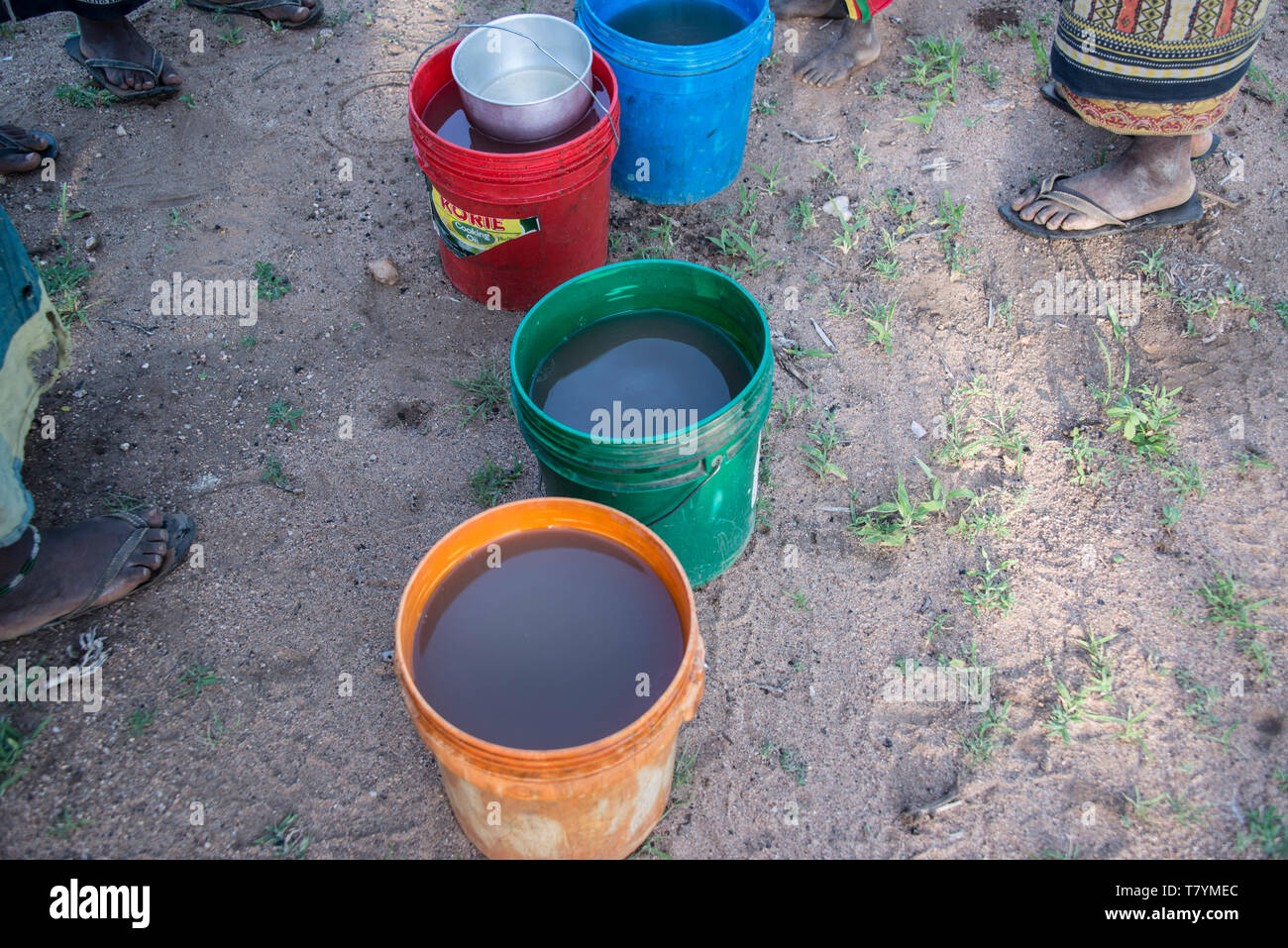 Buckets of unsafe dirty drinking water in jerry cans collected by African village people causes illness, Tanzania, Africa Stock Photo