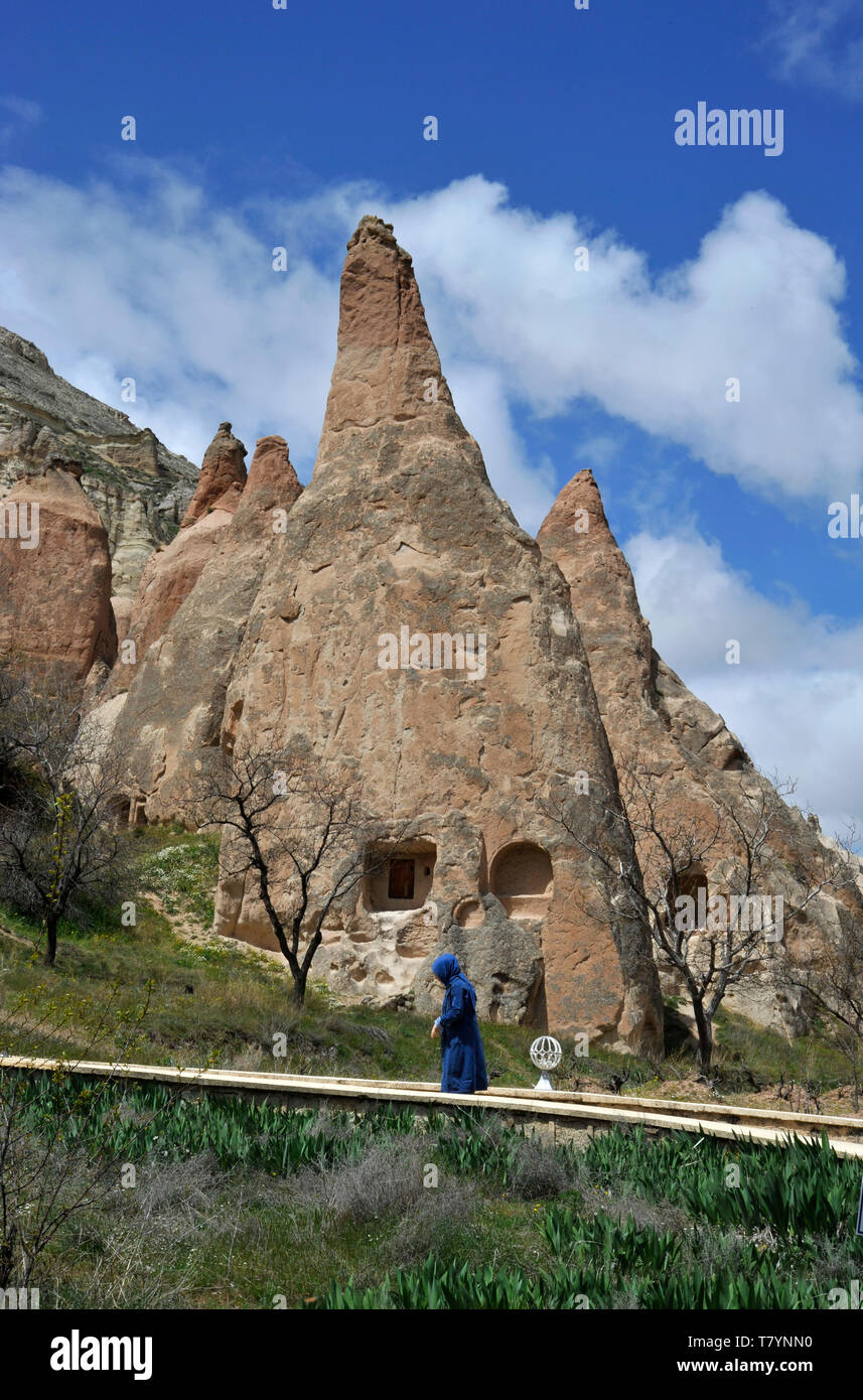 A Muslim woman walks along path through unusual rock formations at outdoor museum in Cappadocia, Turkey Stock Photo