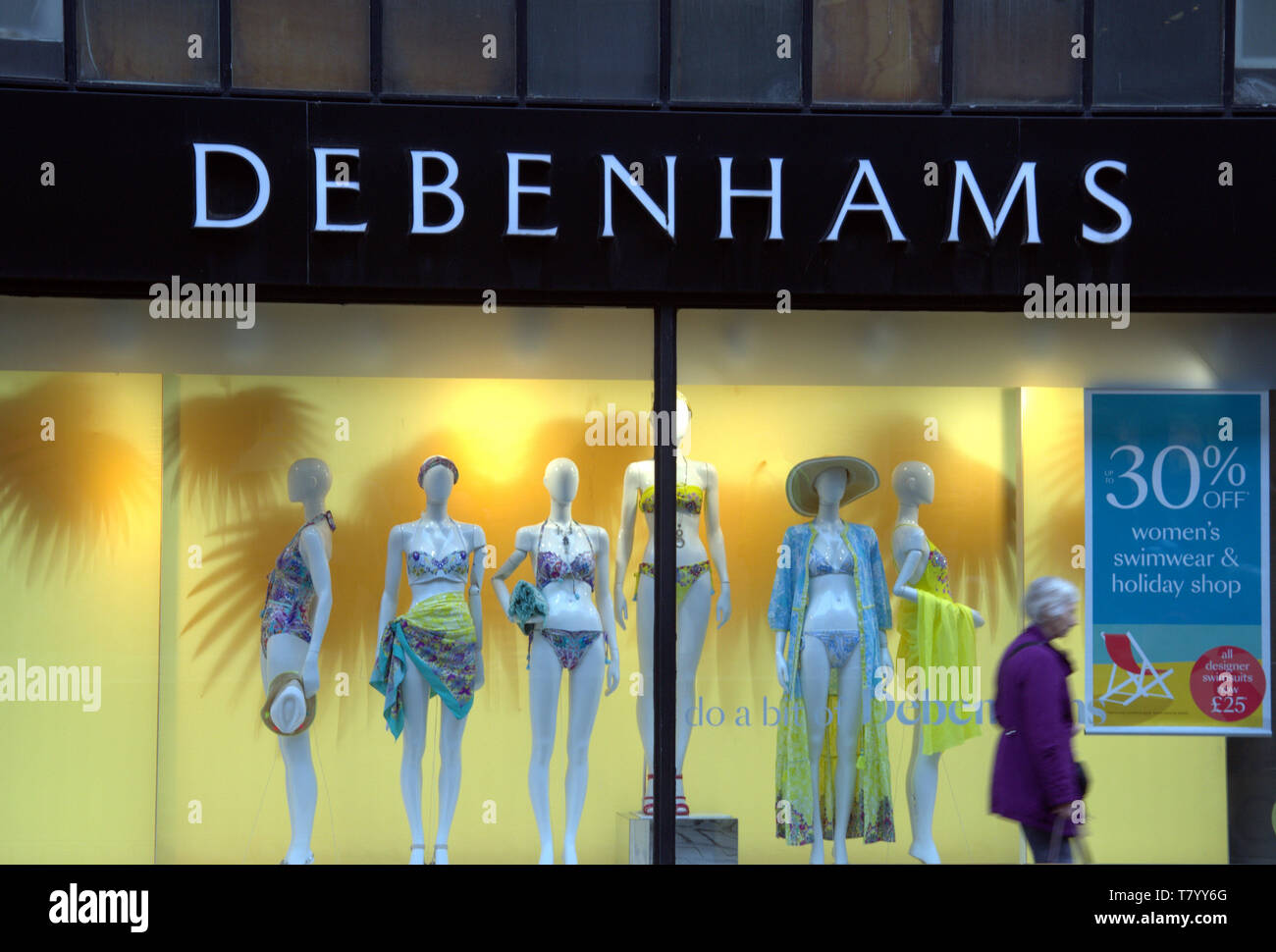 Shop window of Debenham's Department Store, Market Street, Manchester, uk, with a female passer-by in foreground Stock Photo