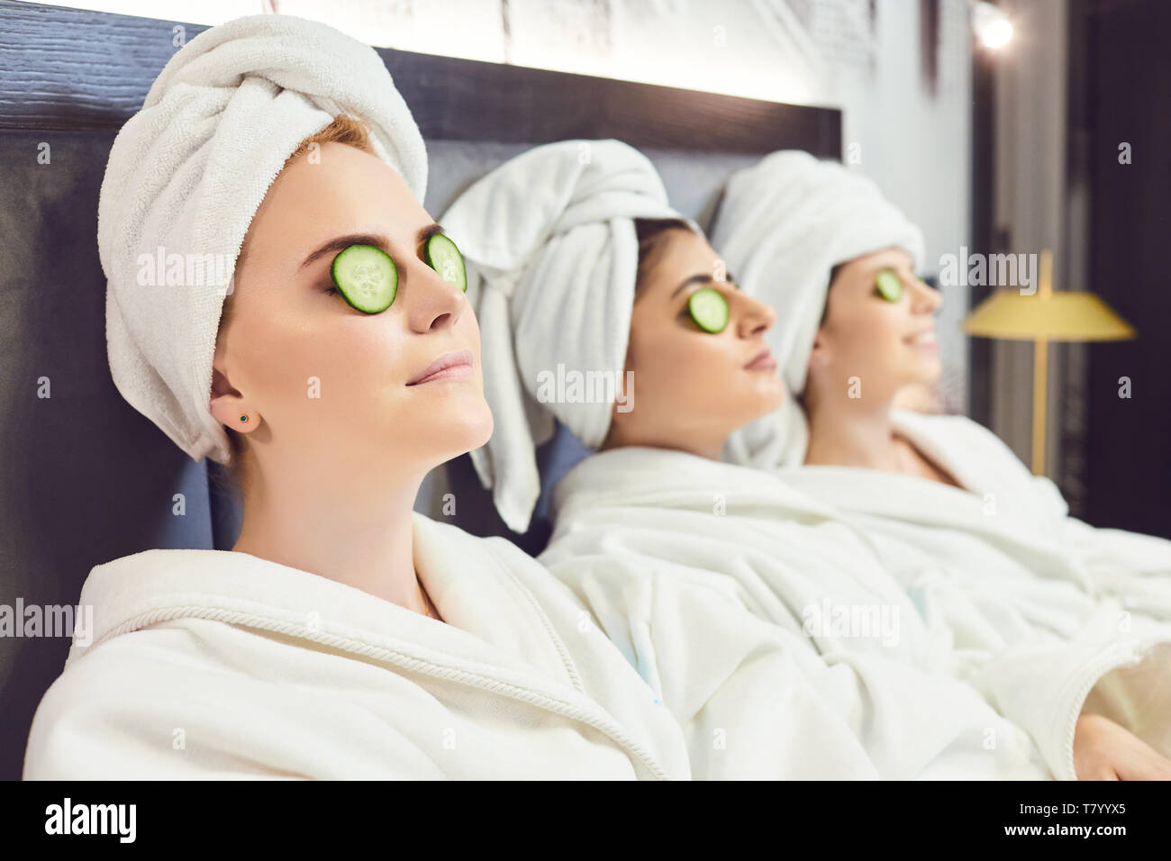 Chilling women in bathrobes with cucumber slices on face  Stock Photo