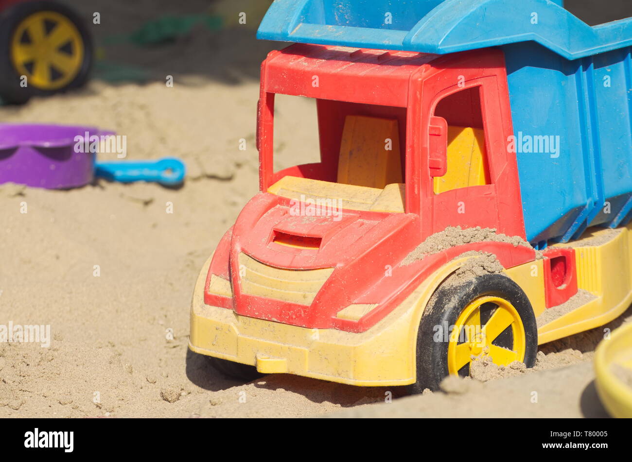 Colorful Plastic Truck Toy in the Sand Closeup Stock Photo
