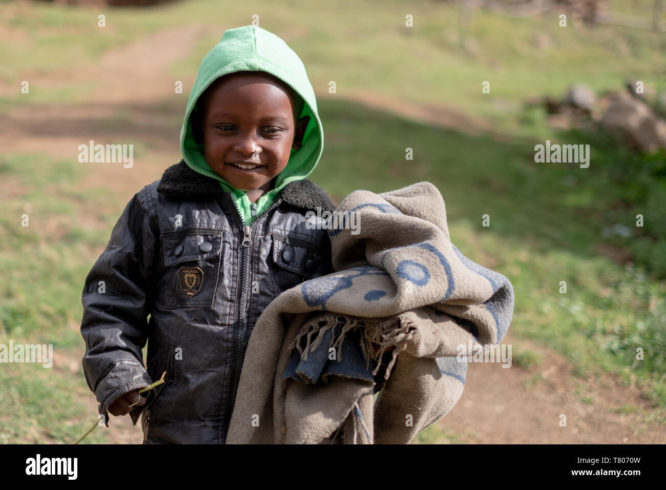 Young boy carrying a blanket in a small village near the town of Mokhotlong in north eastern Lesotho, Africa. Stock Photo