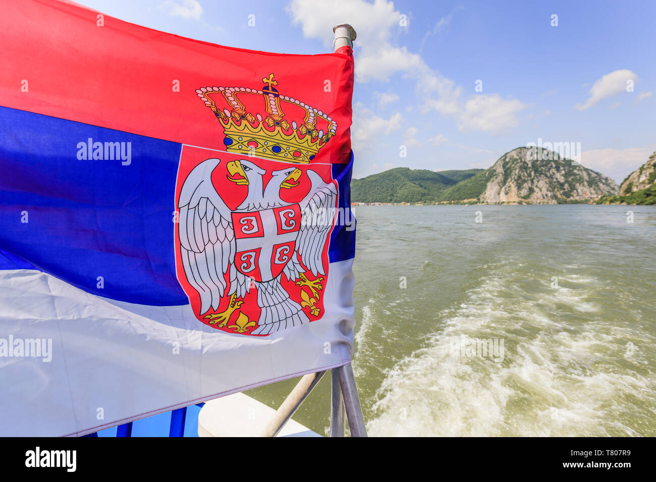 Serbia national flag on tourist boat , Danube river landscape and sky with clouds in background Stock Photo
