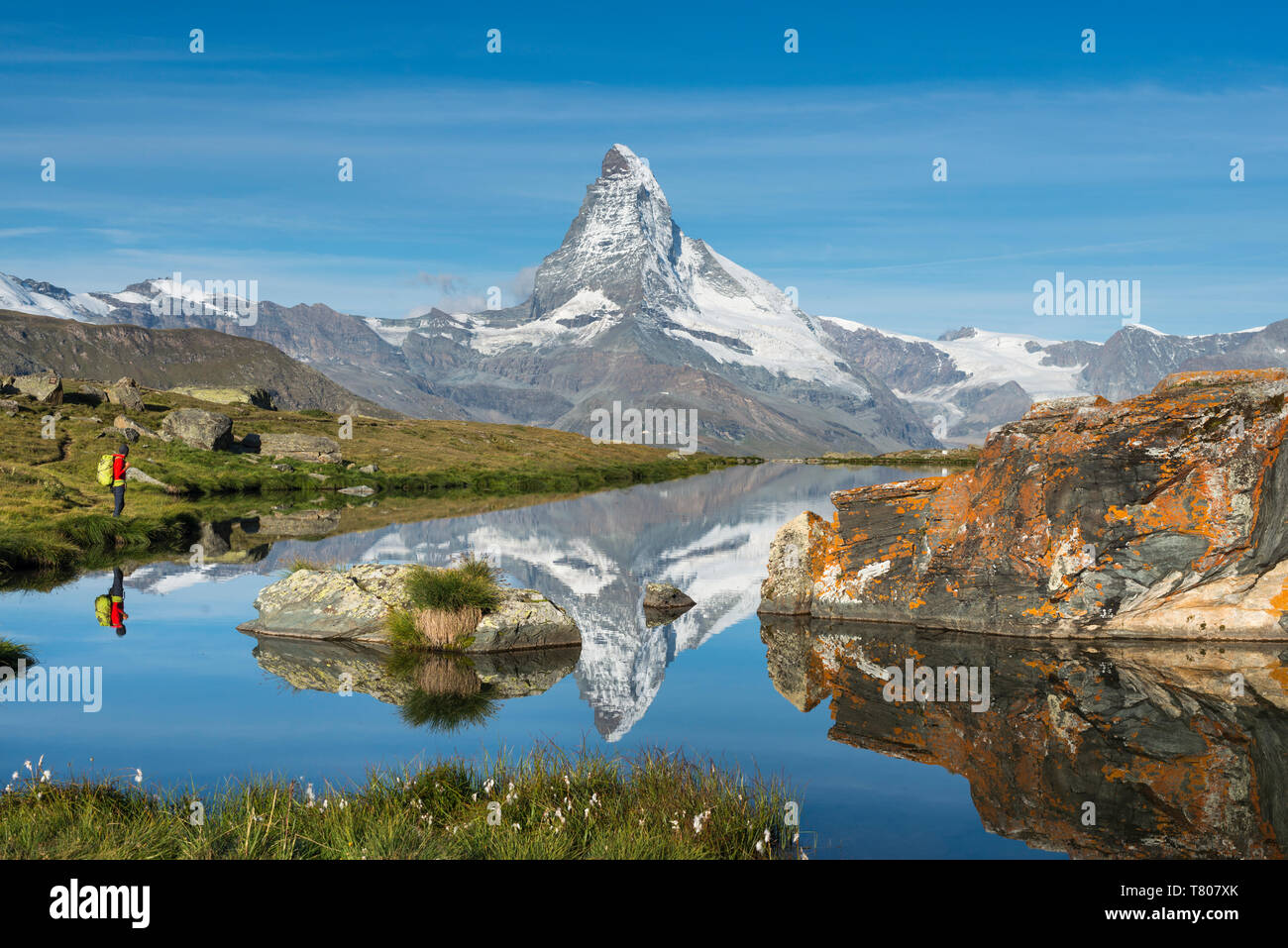 A walker hiking in the Alps takes in the view of the Matterhorn reflected in Stellisee lake at dawn, Swiss Alps, Switzerland, Europe Stock Photo