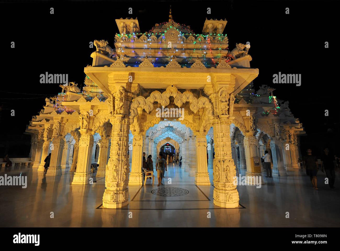 Entrance to the beautiful white marble Swaminarayan Temple, illuminated for evening prayers, Mandvi, Gujarat, India, Asia Stock Photo