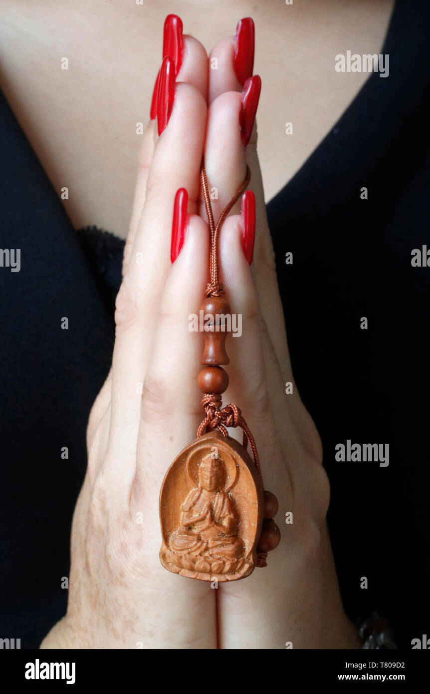 Buddhist woman praying with a wood Buddha pendant in hands, Ho Chi Minh City, Vietnam, Indochina, Southeast Asia, Asia Stock Photo