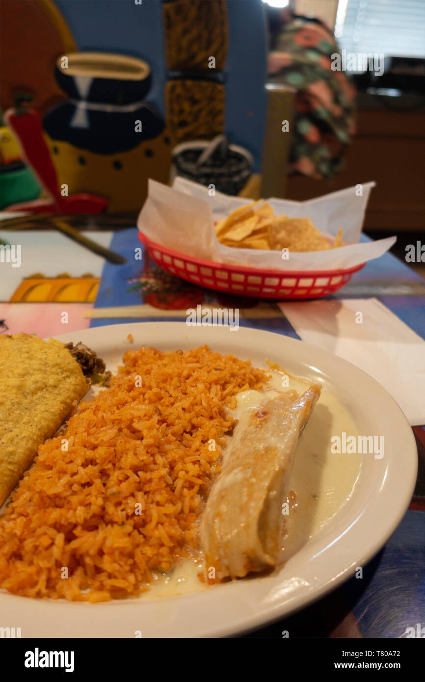 Mexican food on a plate inside a Mexican restaurant, Taco,Spanish rice, and pork tamale. With chips. USA. Stock Photo