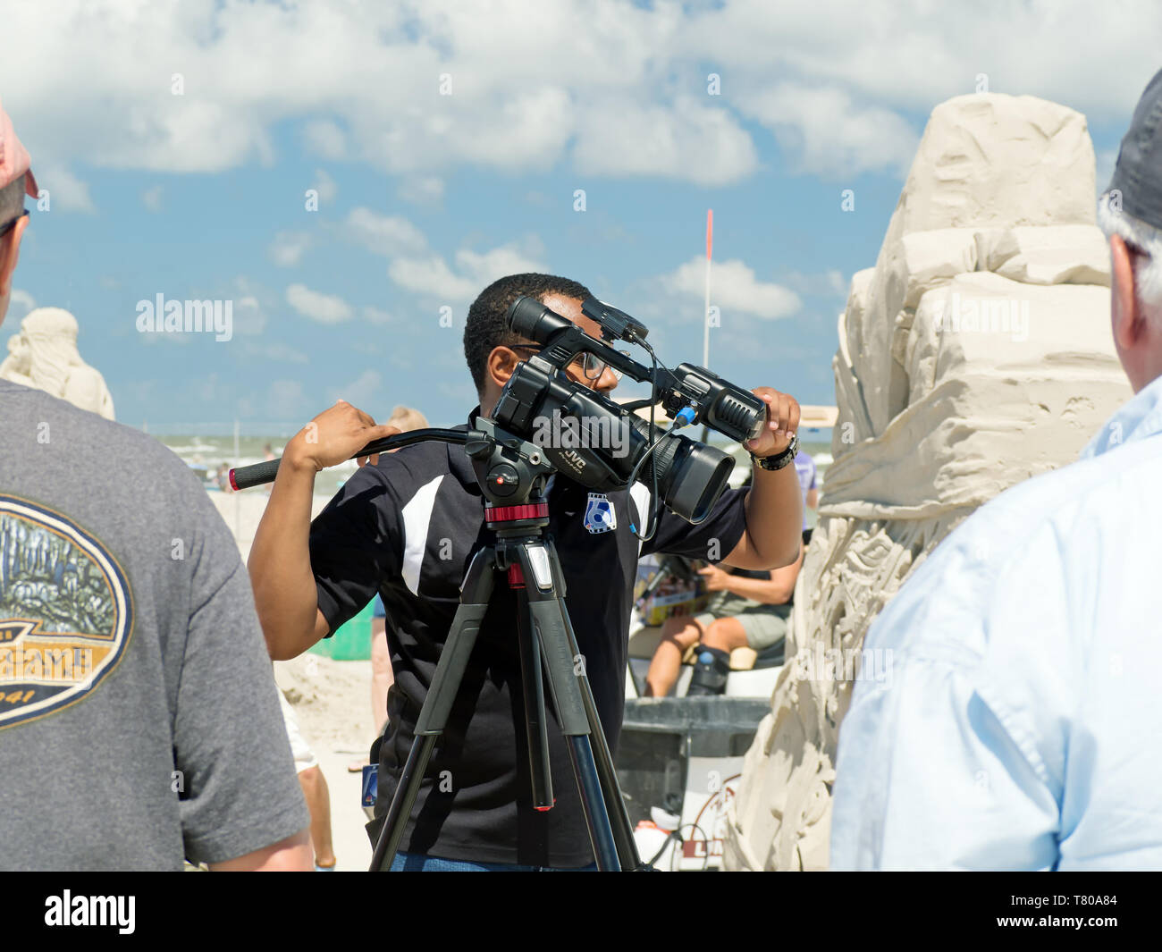 African American photojournalist with JVC video camera from KRIS TV 6 in Corpus Christi covers the 2019 Texas Sandfest in Port Aransas, Texas USA. Stock Photo