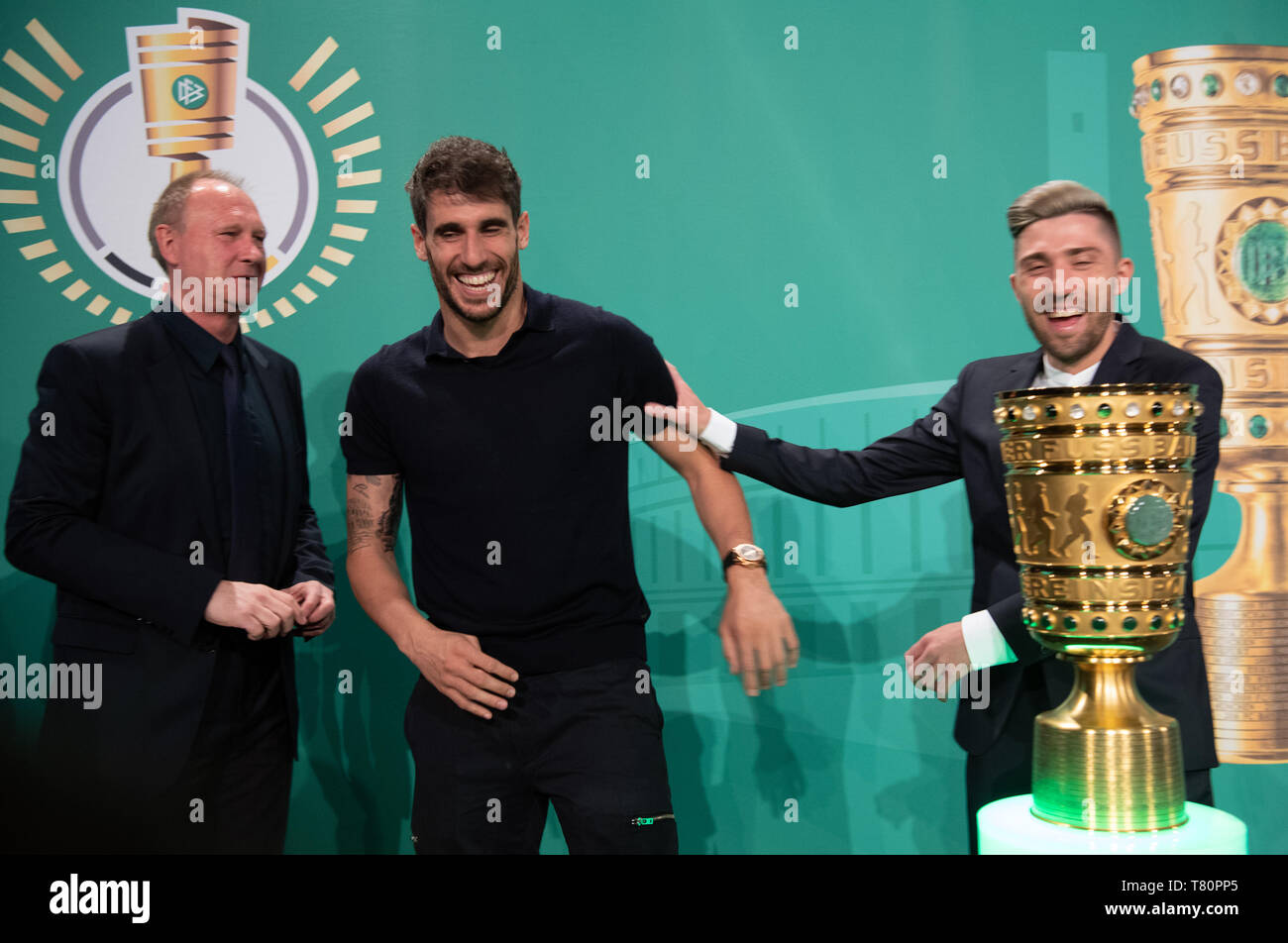Berlin, Germany. 10th May, 2019. Soccer: DFB Cup, Cup Handover of the DFB Cup. Javi Martinez (M), central defender at FC Bayern Munich, and Kevin Kampl (r), midfielder at RB Leipzig, laugh next to the trophy after the event. On the left is Perry Bräutigam, former national goalkeeper of the GDR national team and current goalkeeper scout at RB Leipzig. Credit: Soeren Stache/dpa/Alamy Live News Stock Photo