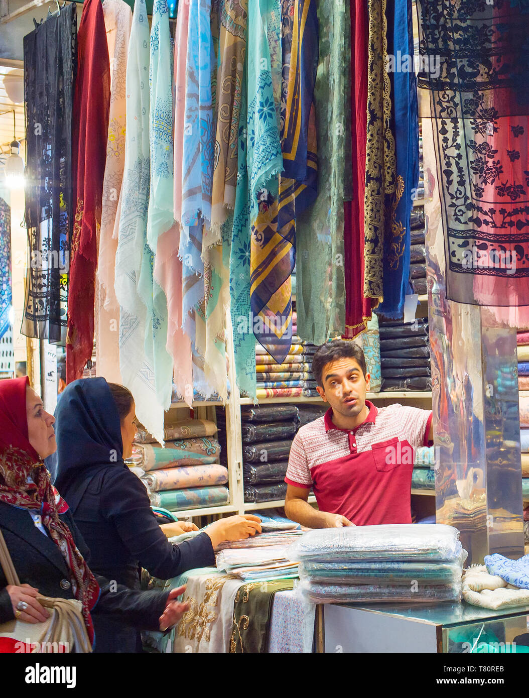 TEHRAN, IRAN - MAY 22, 2017: Woman bying at silk fabrics, textiles and colorful shawls at Grand Bazaar - main market in Tehran Stock Photo