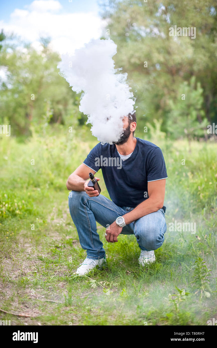 Handsome man smoke electronic cigarette and exhals smoke cloud. Vape Stock  Photo - Alamy
