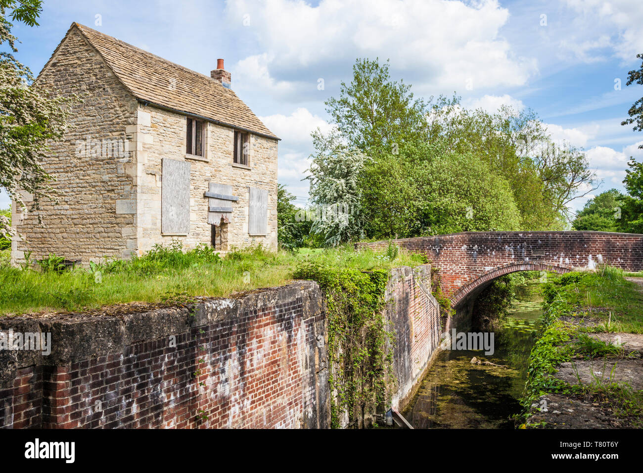 A boarded up Cotswold stone cottage on the banks of the disused Thames and Severn Canal near South Cerney, Gloucestershire. Stock Photo