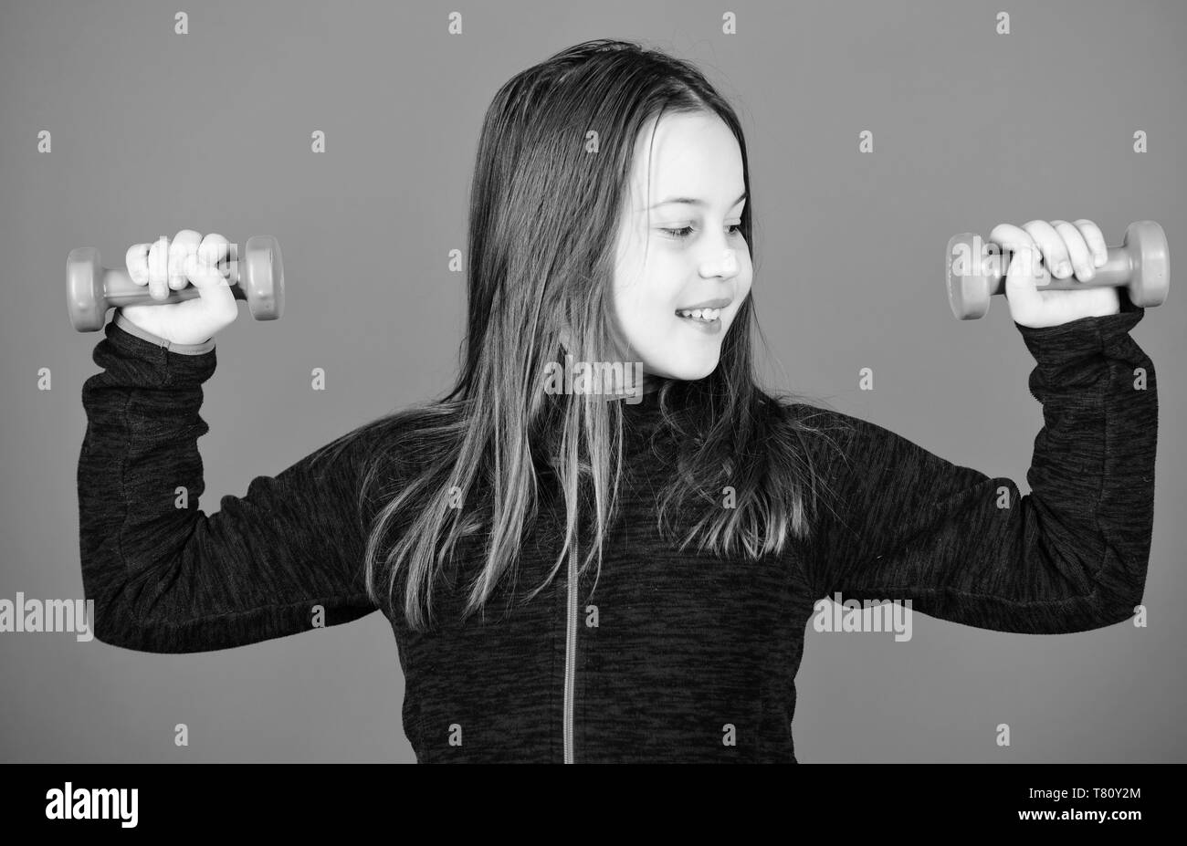 Feeling energy inside. Happy child with barbell. Fitness for energy health. workout of small girl hold dumbbell. weight lifting for muscules. Sport success. full of energy. Young and full of energy. Stock Photo