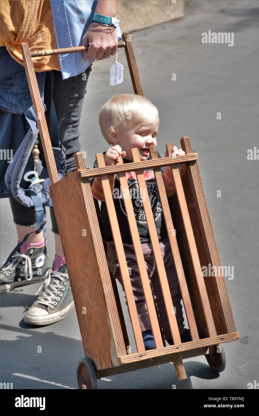 Real toddler boy riding in mom's shopping cart at a street fair in ...