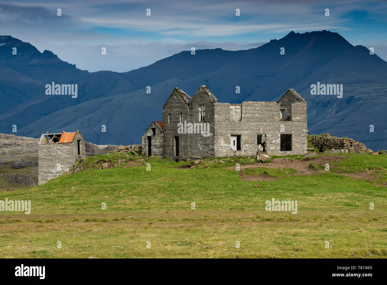 Abandoned farmhouse with mountain backdrop beside the road to Hofn, Eastern Region, Iceland