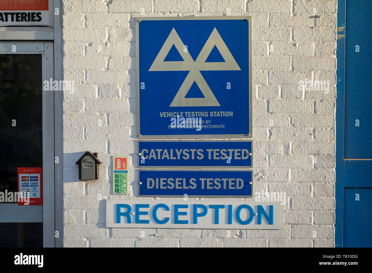 Blue and white signs for MOT vehicle testing station, catalysts tested and diesels tested on the side of a garage. Stock Photo