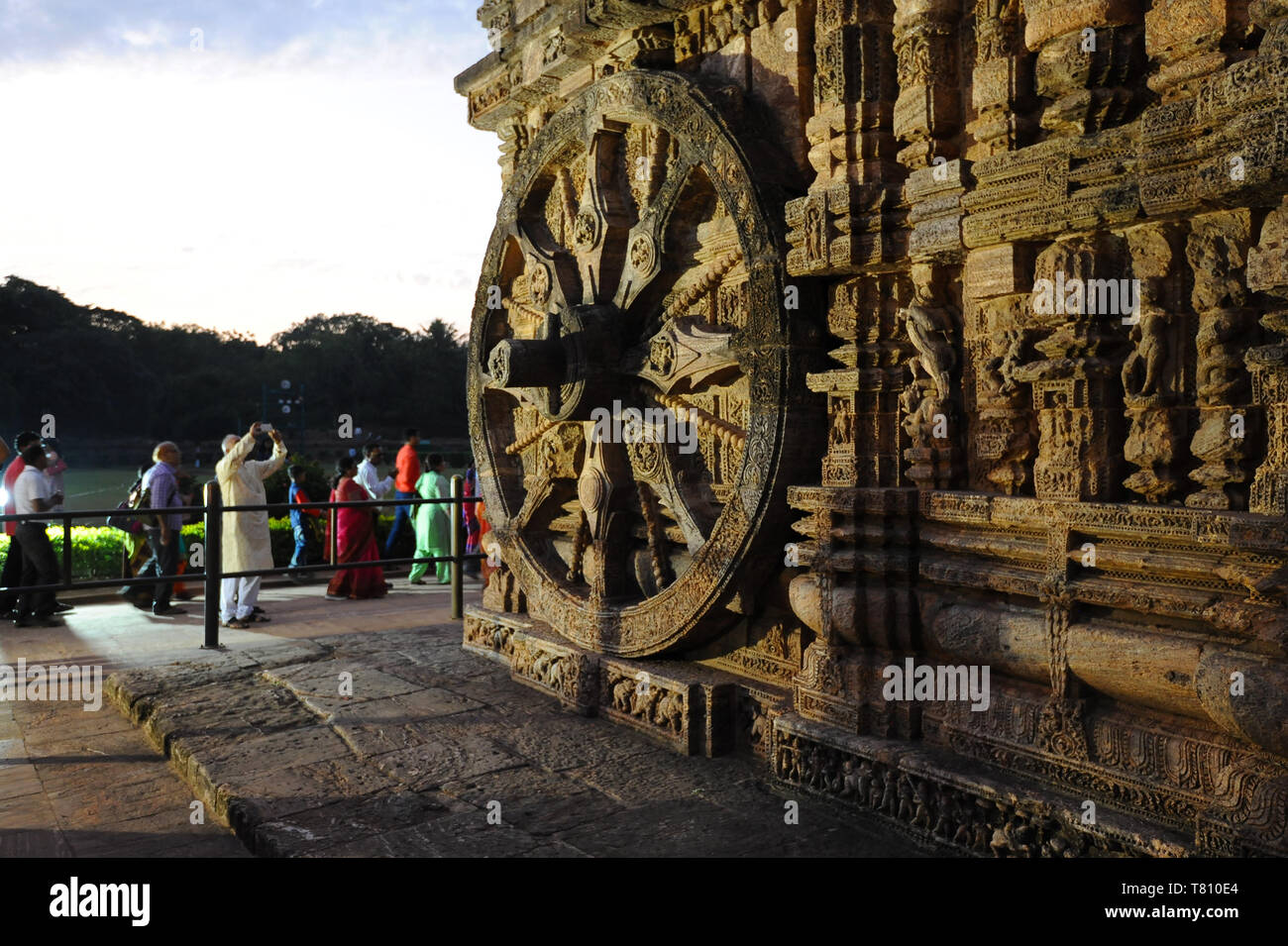 Tourists at sunset by of the 24 carved huge stone chariot wheels carved on 13th century Konark Sun Temple, UNESCO, Odisha, India, Asia Stock Photo