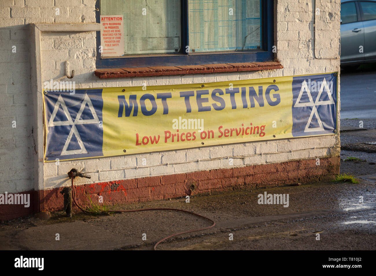 MOT Testing sign on the side of a garage, 'low prices on servicing'. Stock Photo