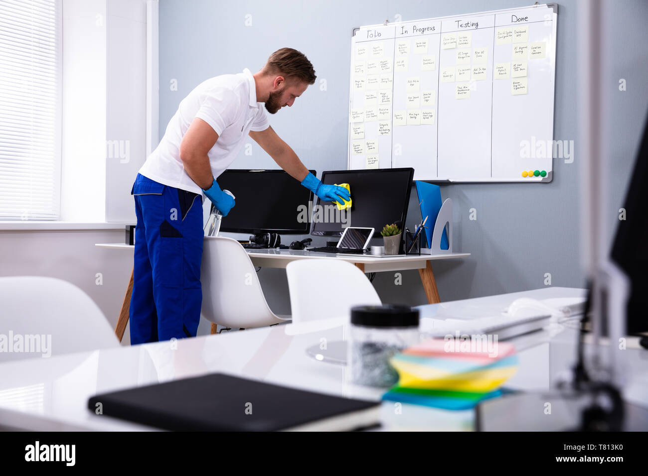 Janitor cleaning white desk in modern office Stock Photo Alamy