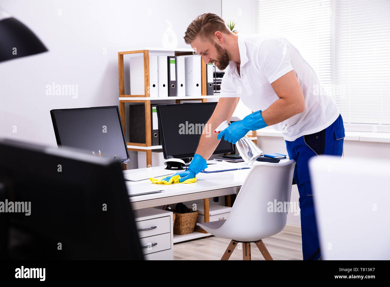 Janitor cleaning white desk in modern office Stock Photo Alamy