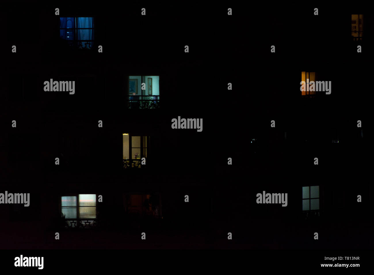 2019, May - Sao Paulo, Brazil. Multiple windows of an apartment building at night. Some yellow, some blue, some light on, some light off. Stock Photo