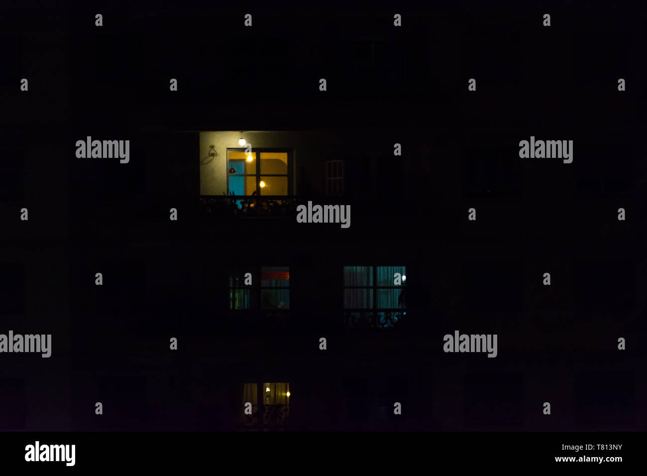 2019, May - Sao Paulo, Brazil. Multiple windows of an apartment building at night. Some yellow, some blue, some light on, some light off. Stock Photo
