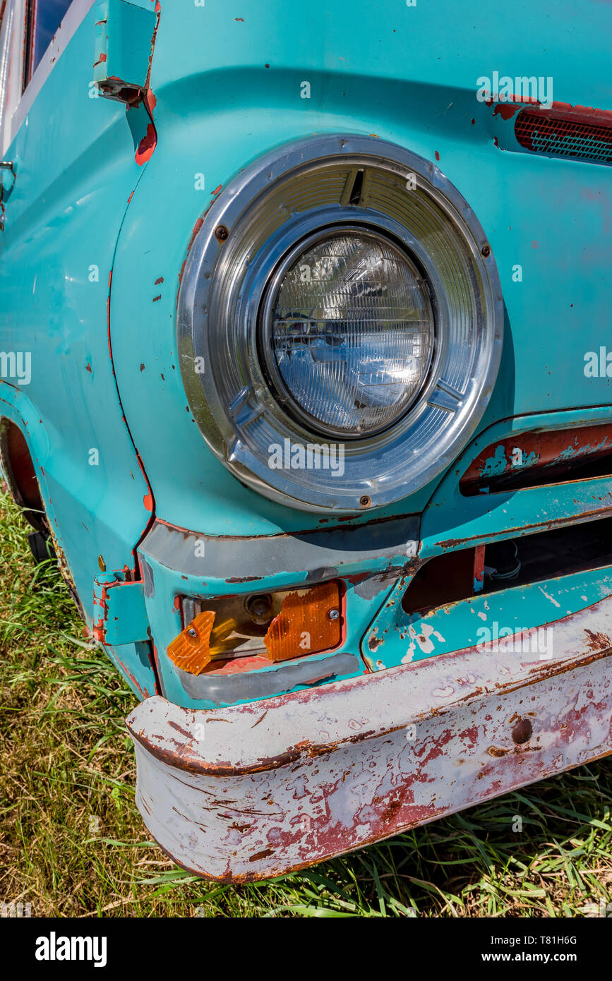 Vintage headlight on an old, abandoned aqua blue van with a rusty