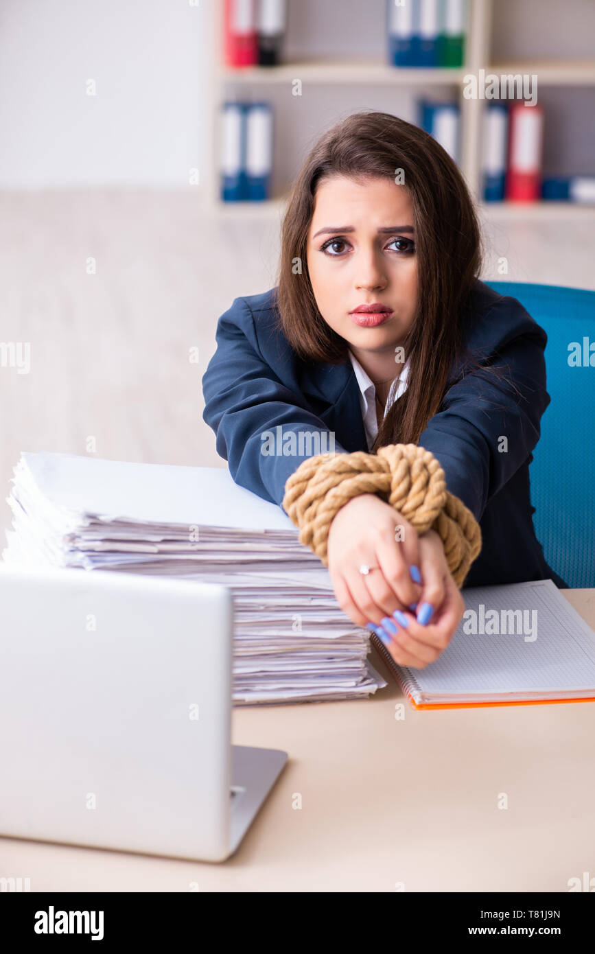 Young beautiful employee tied up with rope in the office Stock Photo