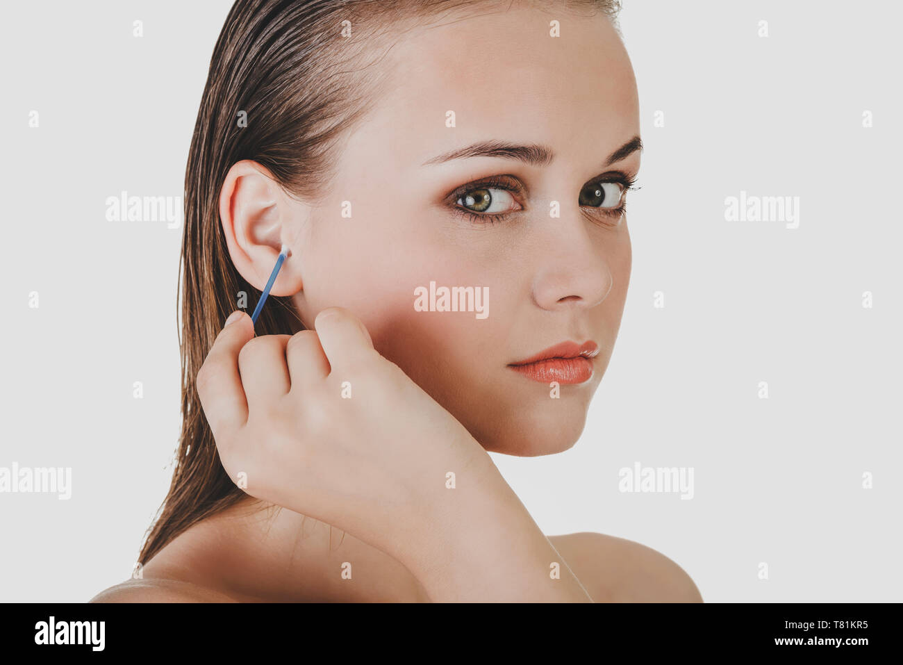 Woman is cleaning ear with a cotton bud on white background Stock Photo