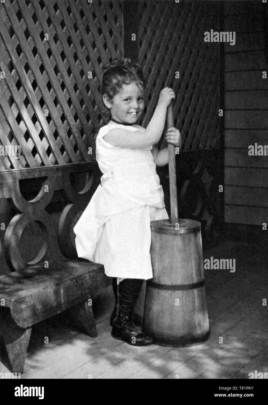 Young Milkmaid Churning Butter, 1900 Stock Photo