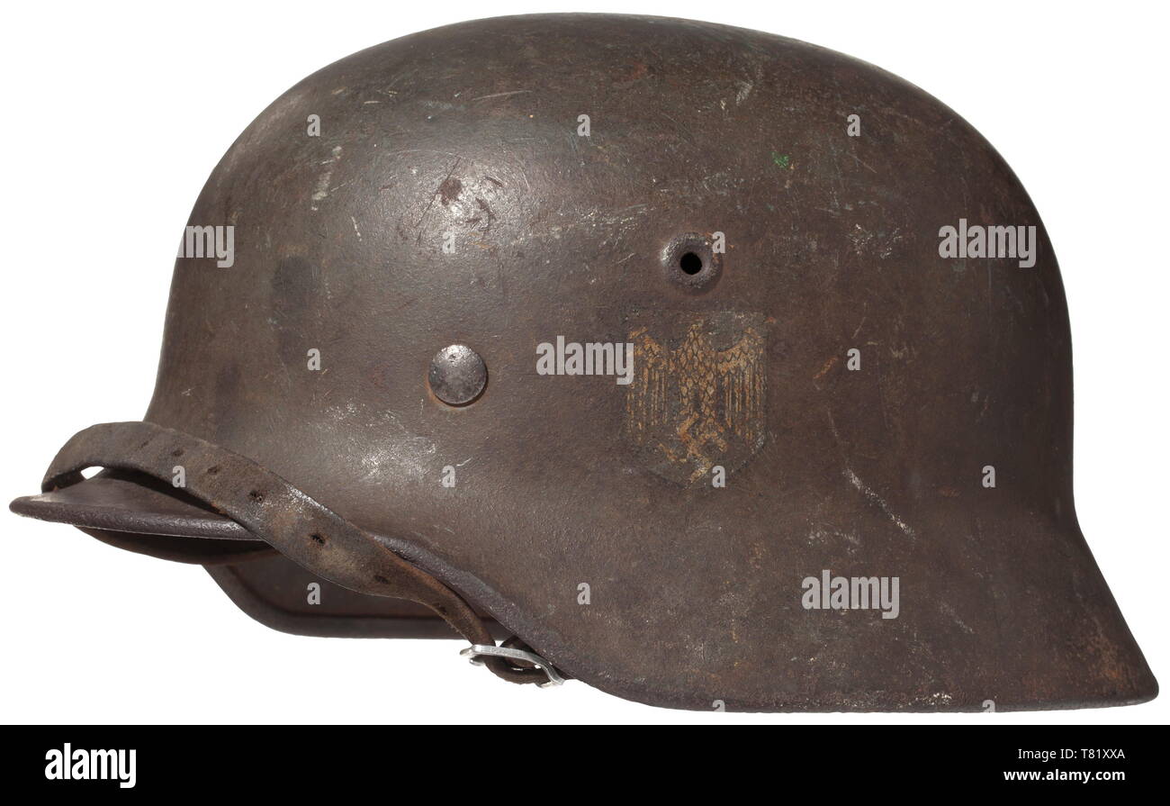 A steel helmet M 40 for 'Blue Division' members - 'Division Espanola de Voluntarios'. Field-grey painted steel shell (rust pitted), the eagle shield up to 60% intact, the troop recognition symbol on the right side in the Spanish national colours up to 80% intact. The shell interior with maker's mark 'Q 64' of the Quist firm, Esslingen. Complete inner liner with chin strap. historic, historical, army, armies, armed forces, military, militaria, 20th century, Editorial-Use-Only Stock Photo