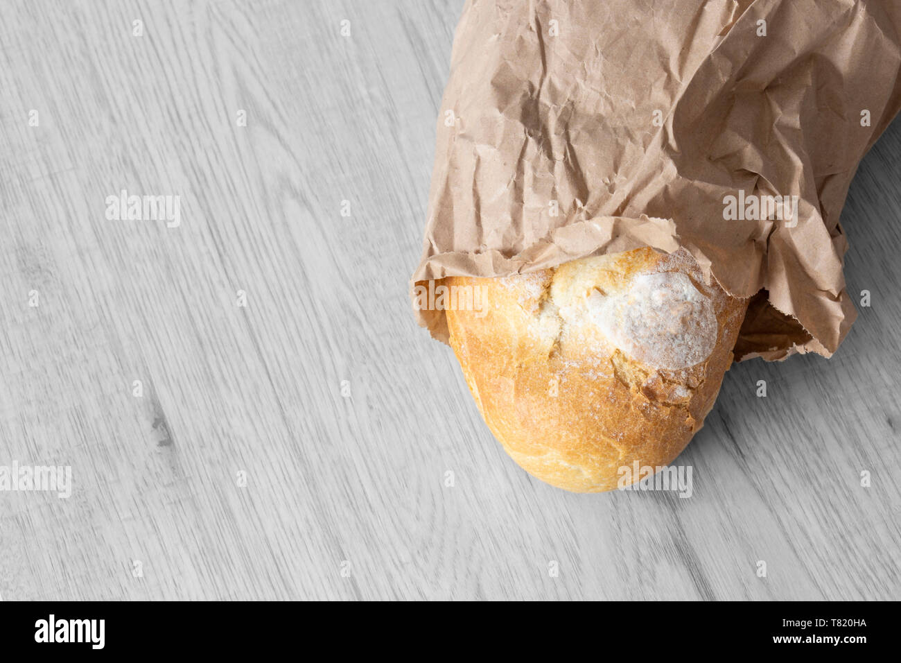 Loaf of white bread in a brown paper bag on grey wood. Recycle ...