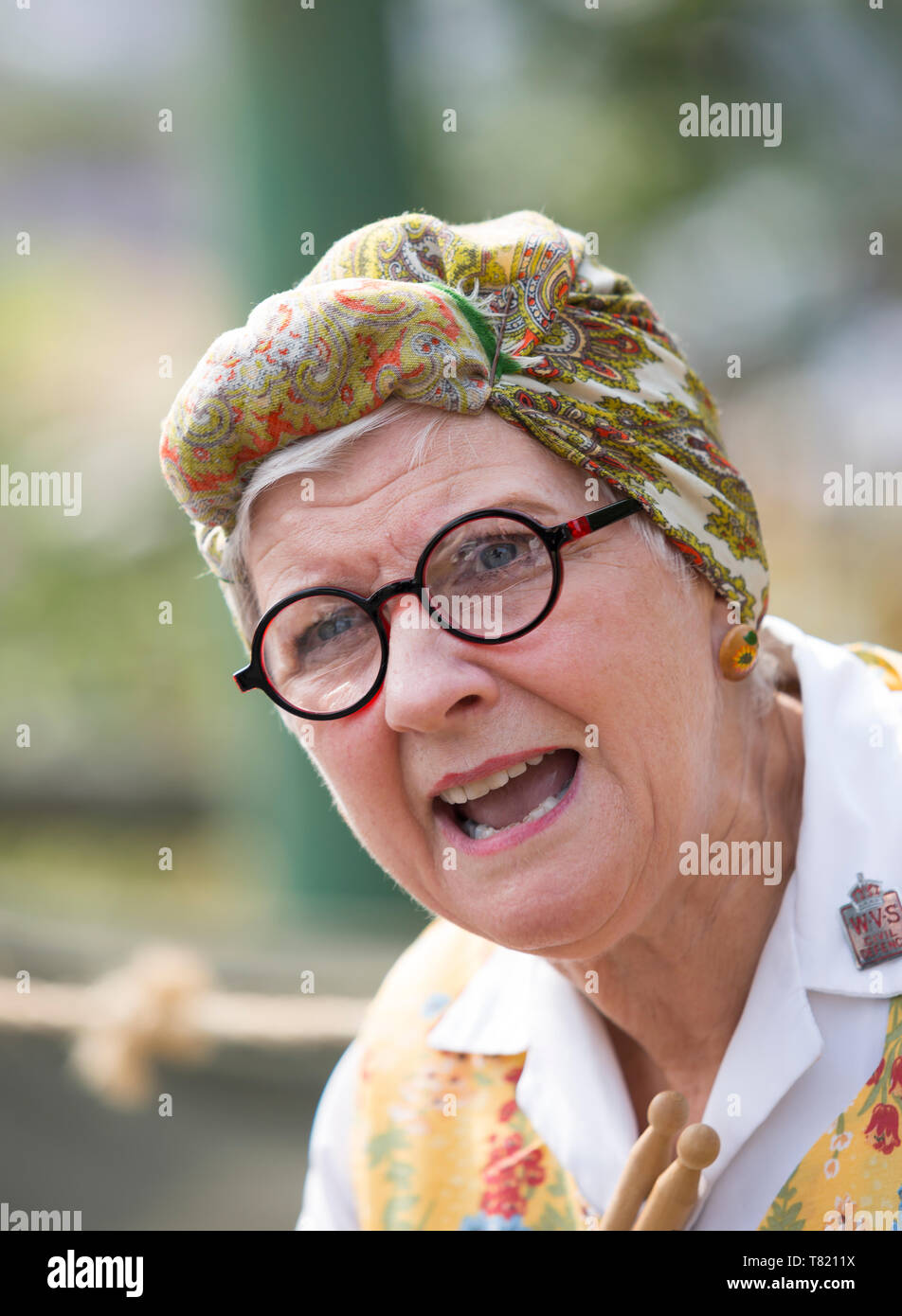 Close-up front view portrait of isolated Caucasian woman in headscarf & overalls as authentic vintage housewife, charlady Mrs Mop at 1940's WWII event. Stock Photo