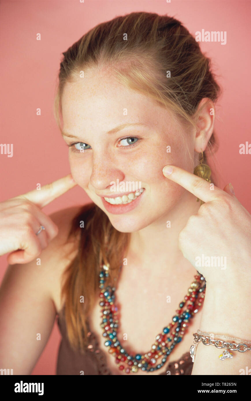 Cute Teenage Girl Pointing to her Dimples with  a big smile, USA Stock Photo