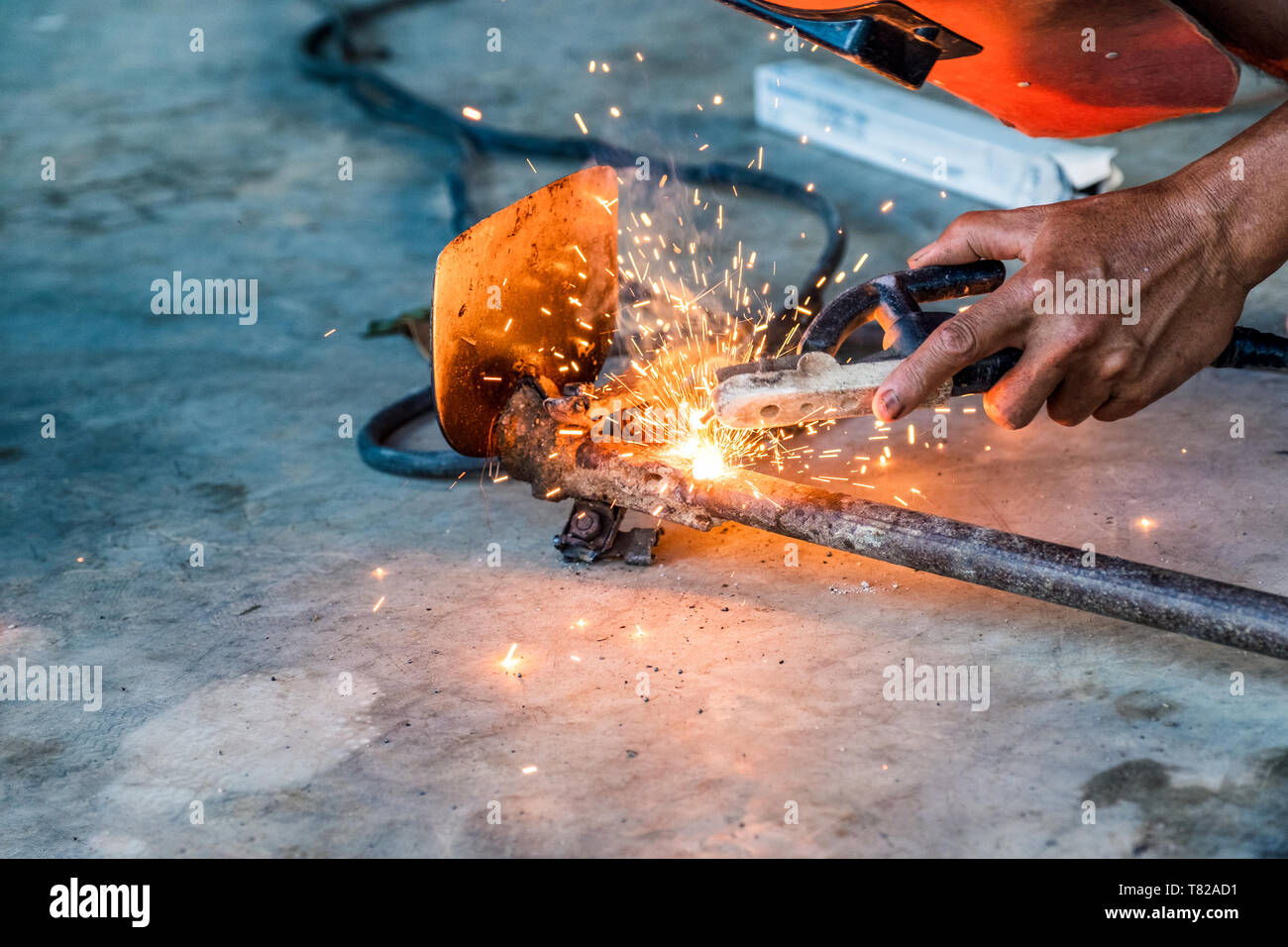 Industrial worker using welder machine is welding a spade tool with sparking Stock Photo