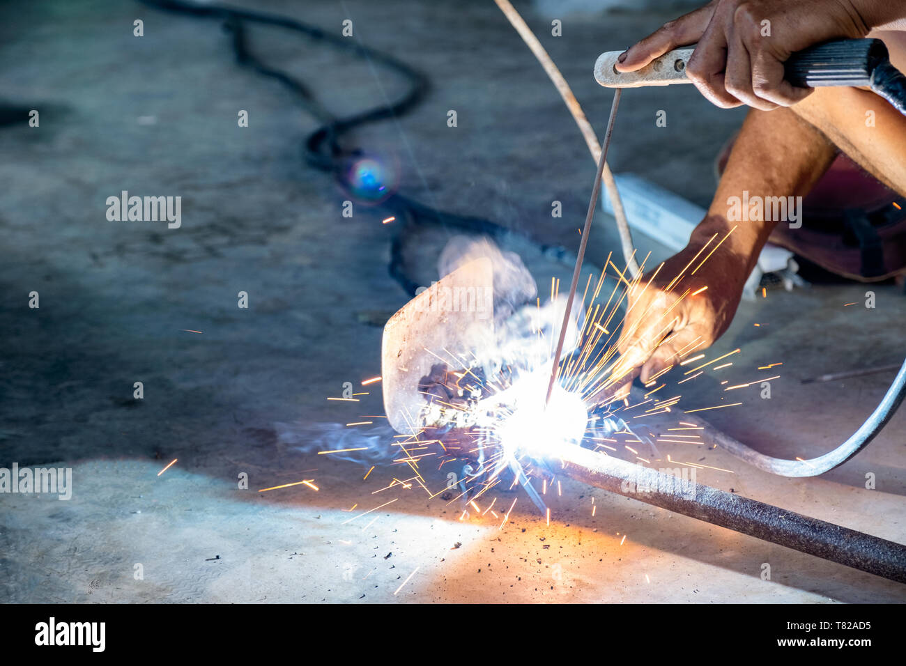 Industrial worker using welder machine is welding a spade tool with sparking Stock Photo