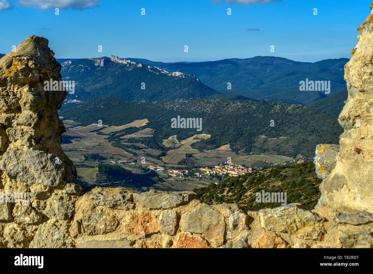 The view to Chateau Peyrepertuse, from the ruined medieval Queribus Castle, in the Pyrenees Orientales, France. Cucugnan village is in the foreground. Stock Photo