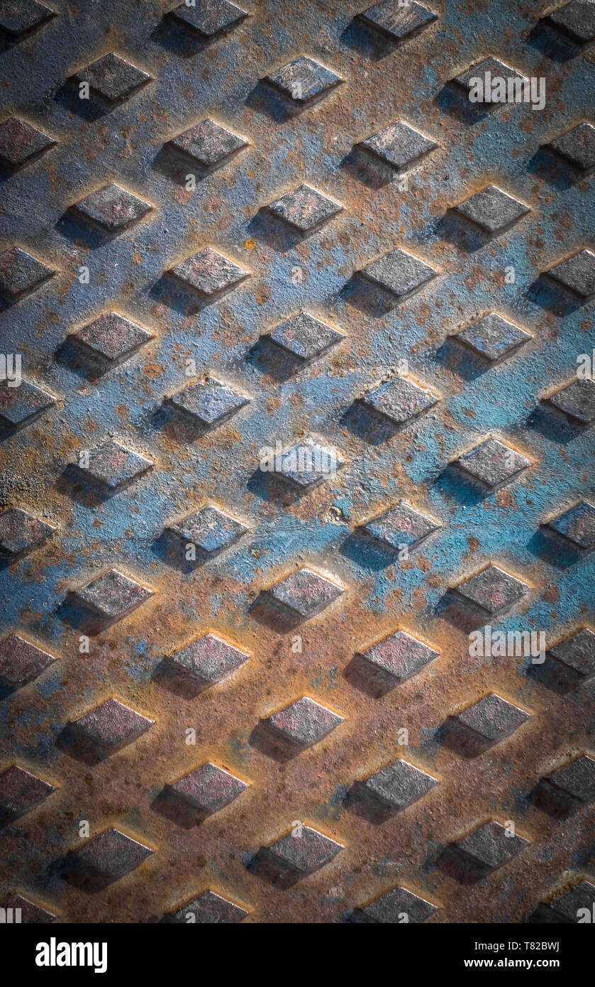 Old rusty drain cover background with diamond pattern. Stock Photo