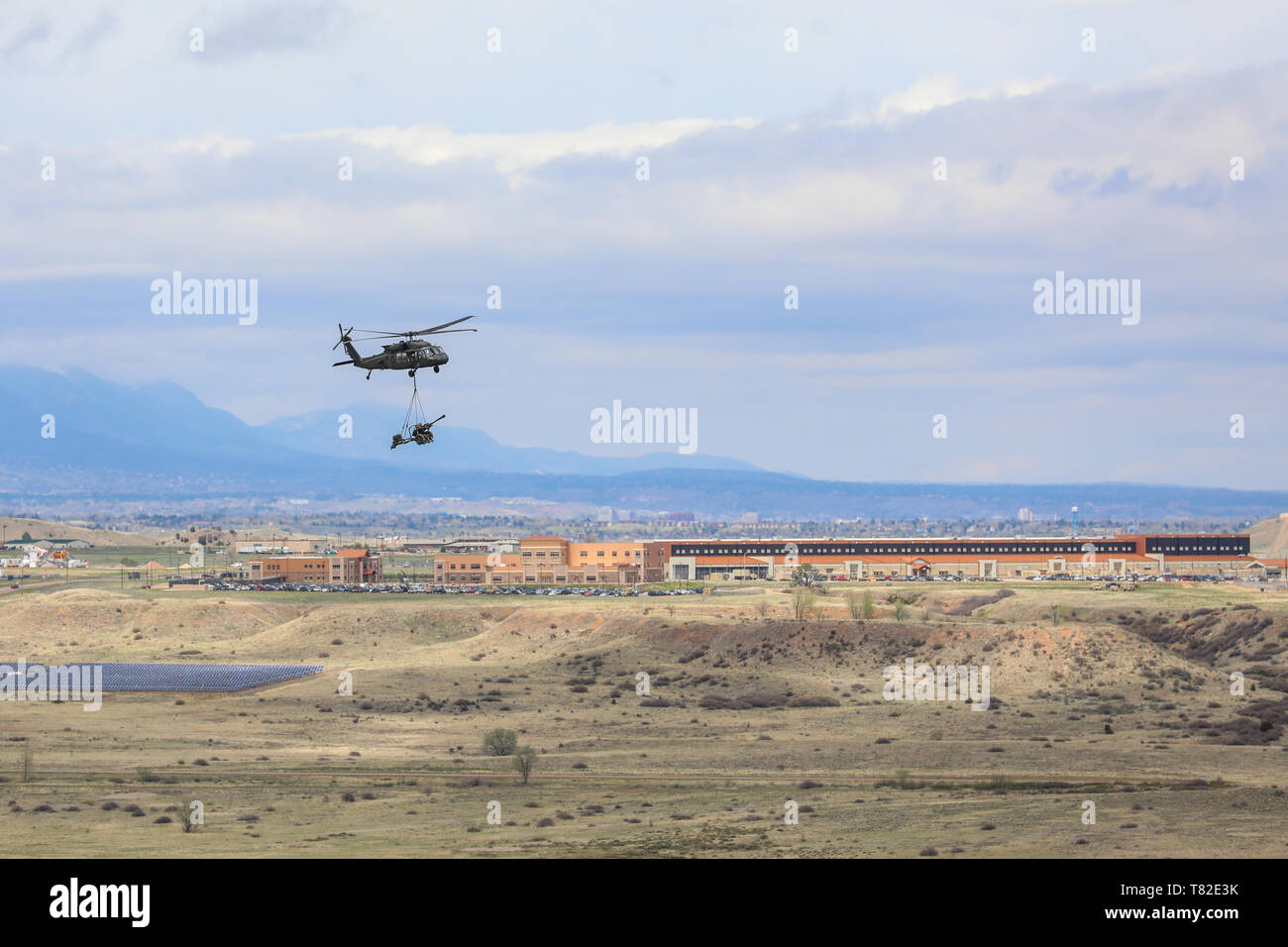 A UH-60 Black Hawk, piloted by members of the 4th Combat Aviation Brigade, 4th Infantry Division, picks up a M119 Howitzer, May 2, 2019, during air assault training with Soldiers Bravo Battery, 2nd Battalion, 77th Field Artillery Regiment, 2nd Infantry Brigade Combat Team, 4th Inf. Div., on Fort Carson, Colorado. (U.S. Army photo by Staff Sgt. Neysa Canfield) Stock Photo