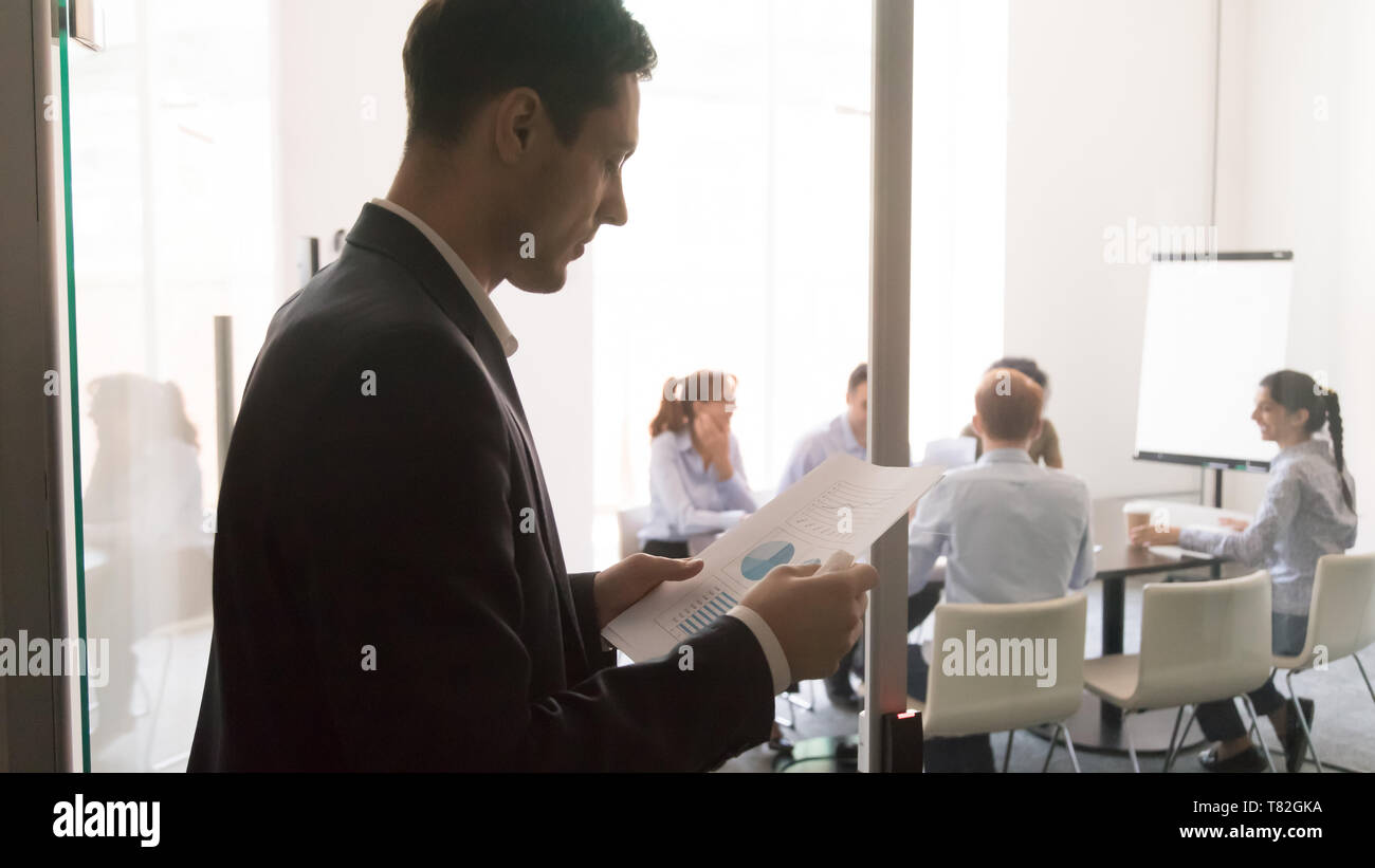 Worried male presenter reading paperwork before presentation Stock