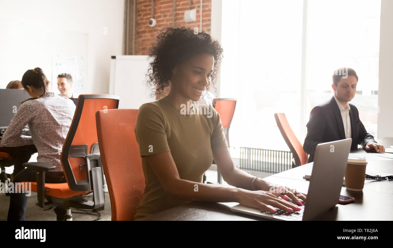 Smiling black female employee working on laptop in shared office Stock ...