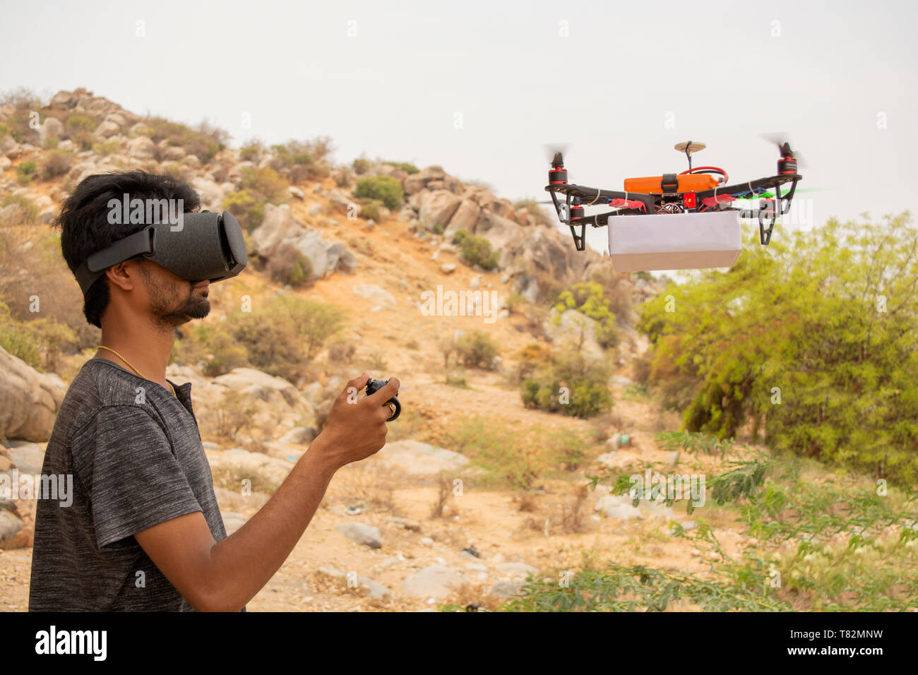 Young man trying to control drone by controller by seeing at virtual reality viewer. Stock Photo
