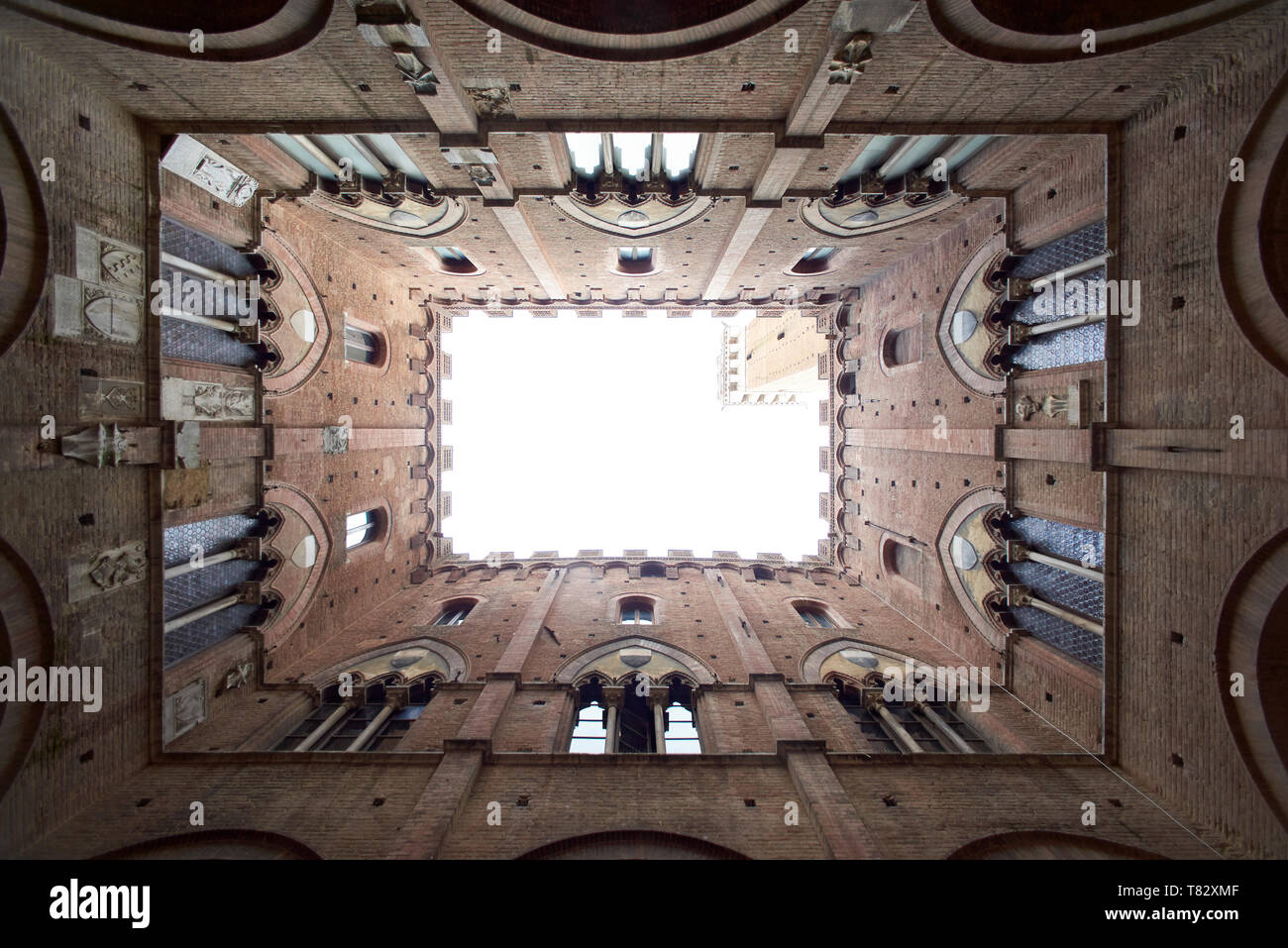 Amazing angle looking up inside the Torre del Mangia tower in the city centre of Siena in Toscany in bright summer sunshine Stock Photo